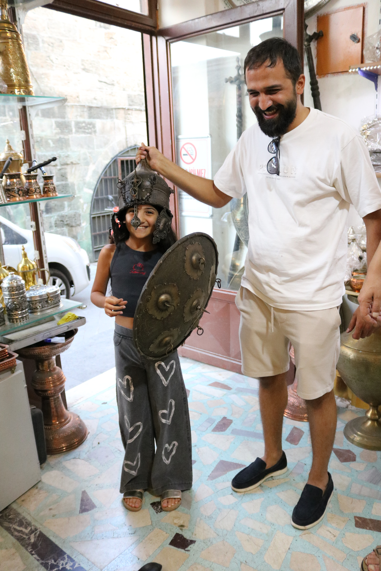 A local host sharing a moment with a young guest in a copper shop